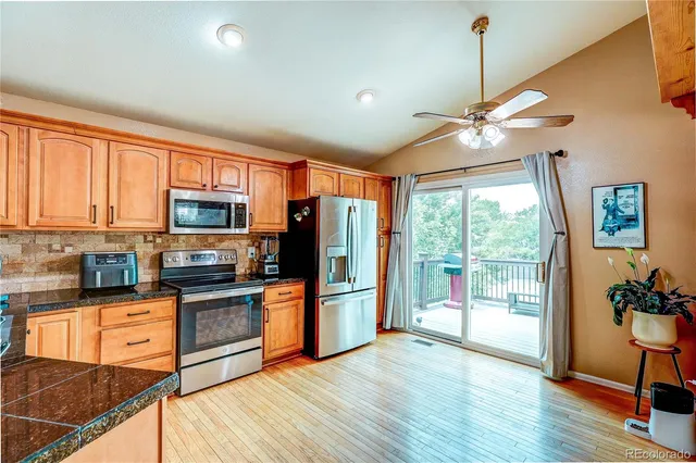 a kitchen with stainless steel appliances granite countertop a refrigerator a stove top oven a sink and wooden floors