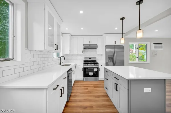 a large kitchen with stainless steel appliances kitchen island granite countertop a sink a stove and a refrigerator