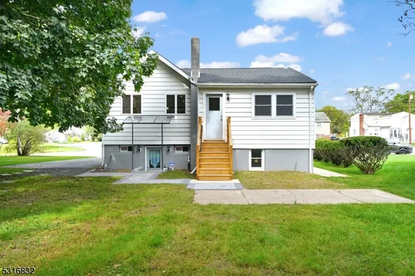 a view of a house with a small yard and a large tree