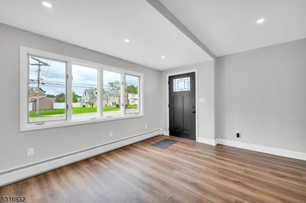 a view of an empty room with wooden floor and a window