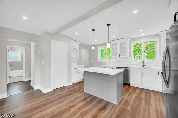 a kitchen with stainless steel appliances a sink stove and wooden floor