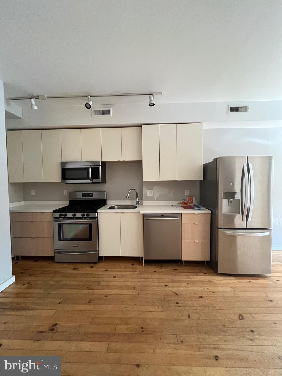 a kitchen with stainless steel appliances a stove top oven a refrigerator and white cabinets
