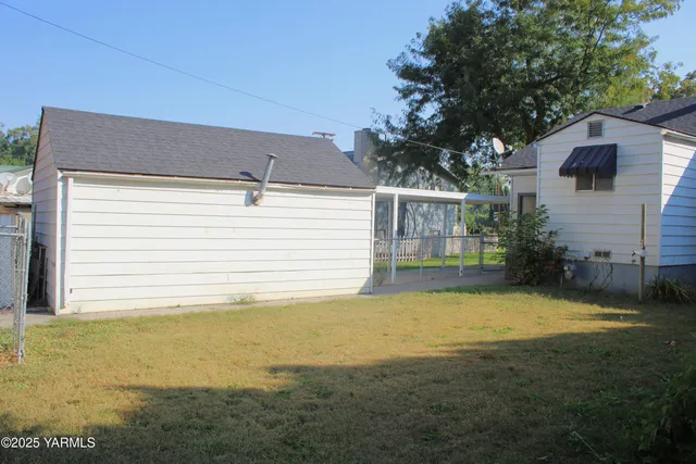 a view of a backyard with plants and large tree