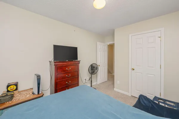 a bedroom with a bed and a flat tv screen on dresser