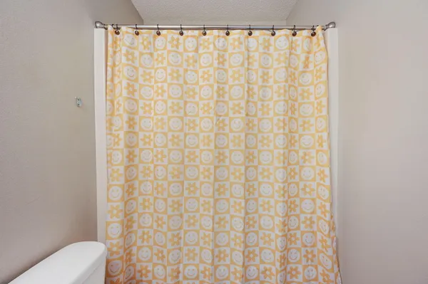 a bathroom with a shower curtain and a toilet next to a window