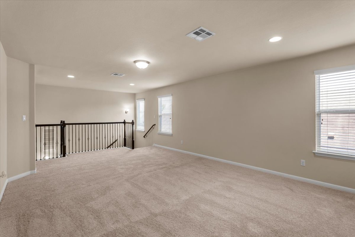 3451 Mayfield Ranch Boulevard, Unit 311 Round Rock, TX 78681 - Photo 24 of 40 Carpeted loft area featuring a wrought iron railing, multiple windows with blinds, recessed lighting, and a flush mount ceiling fixture
