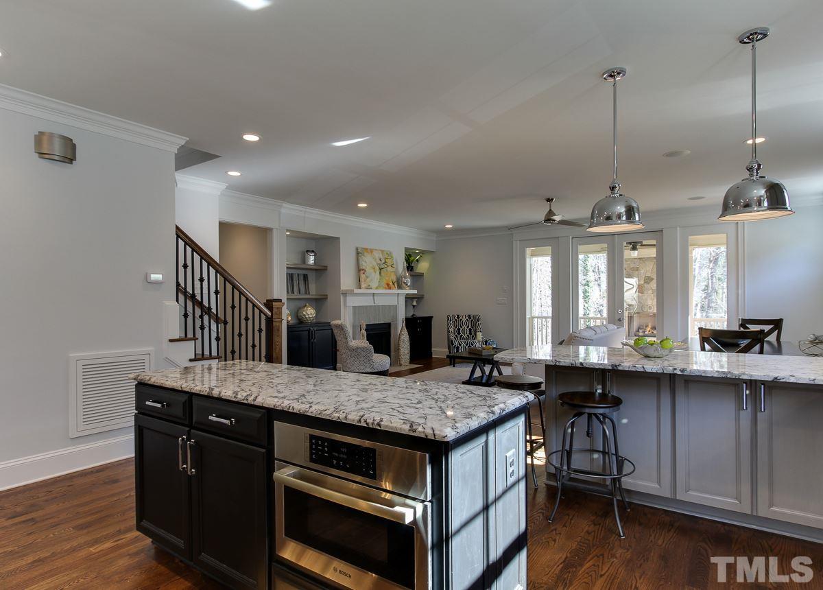 8800 Breeland Way Raleigh, NC 27613 - Photo 6 of 24 a kitchen island with granite countertop a sink and a wooden floor