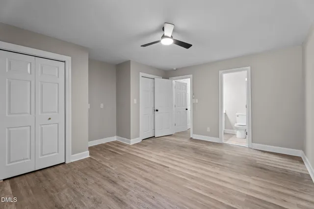 an empty room with wooden floor ceiling fan and windows