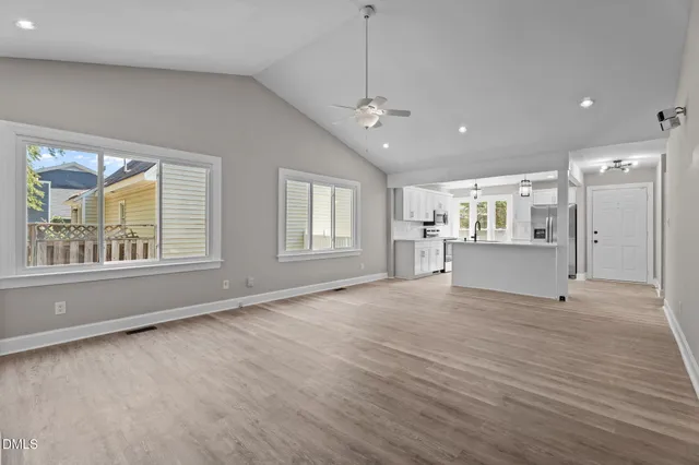 an empty room with wooden floor a fireplace and windows