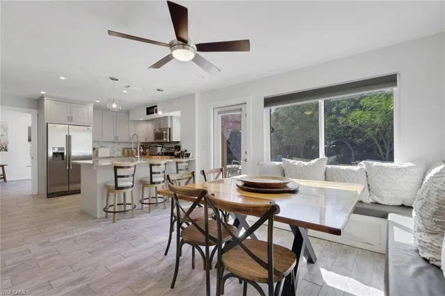 a kitchen with stainless steel appliances granite countertop a stove a refrigerator a oven a sink a dining table and chairs with wooden floor