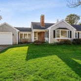 a front view of a house with a garden and trees