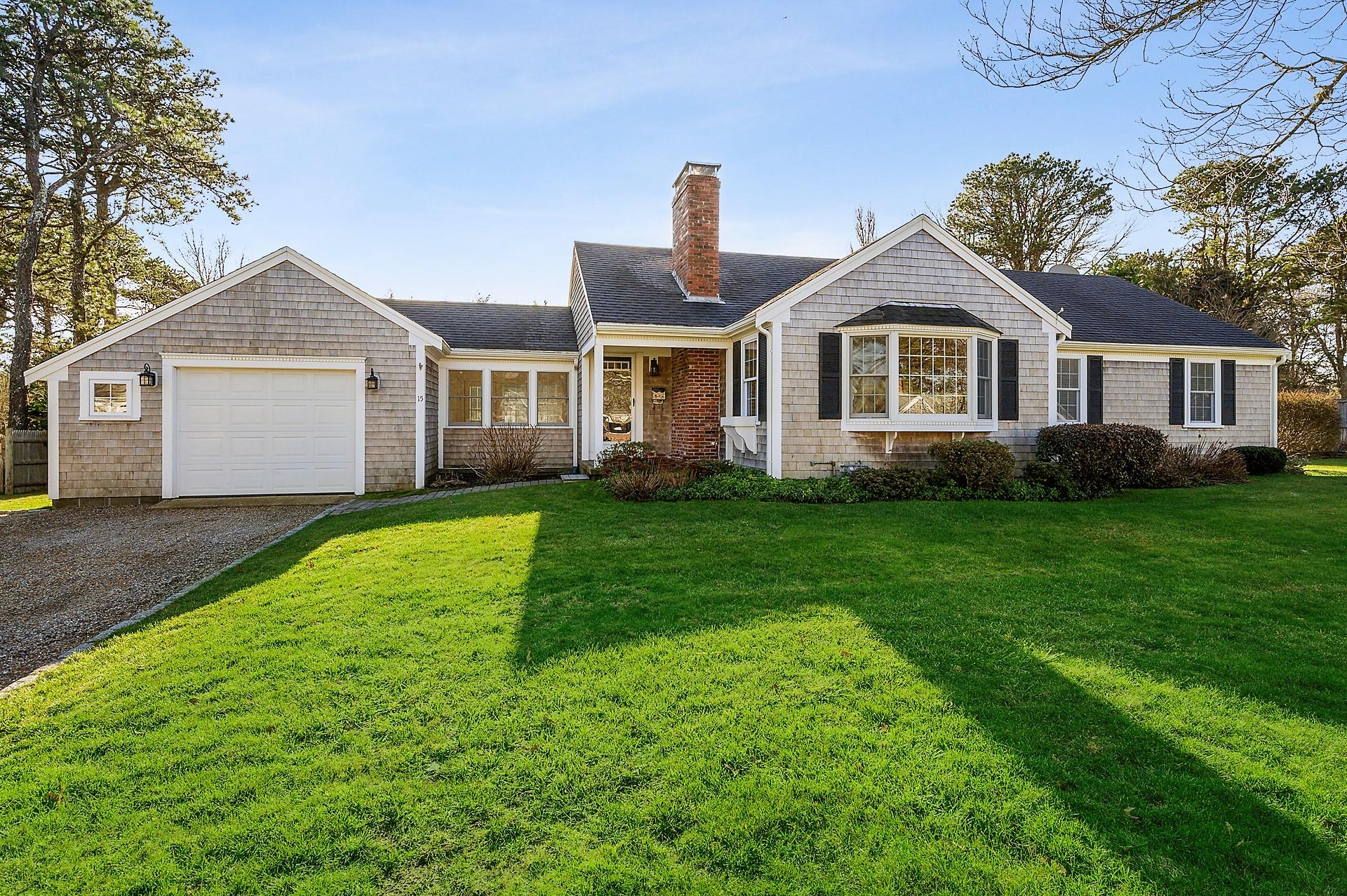 a front view of a house with a garden and trees
