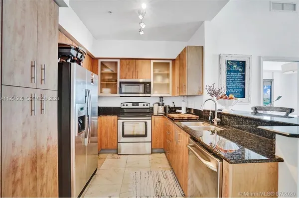 a kitchen with stainless steel appliances granite countertop a sink stove refrigerator and cabinets