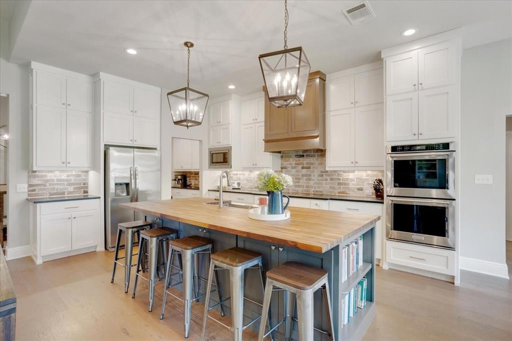 425 Ridgeview Road Sherman, TX 75092 - Photo 13 of 40 a kitchen with stainless steel appliances granite countertop a stove refrigerator and white cabinets with wooden floor
