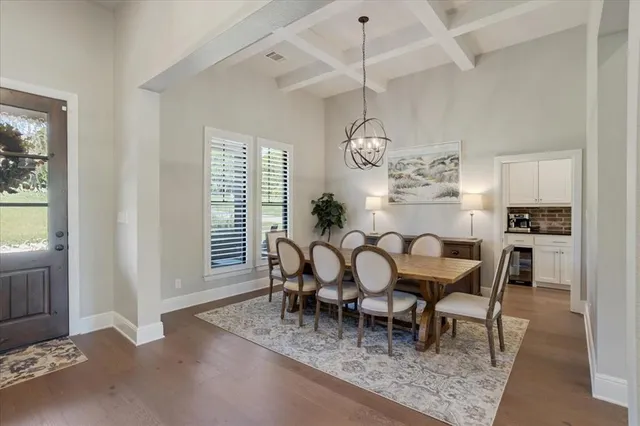 a dining room with wooden floor a chandelier a wooden table and chairs