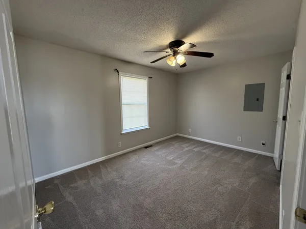an empty room with windows and fan