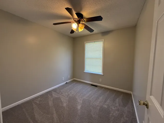 an empty room with windows and fan