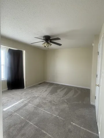 a view of an empty room with a chandelier fan