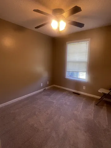 an empty room with a window and a fan