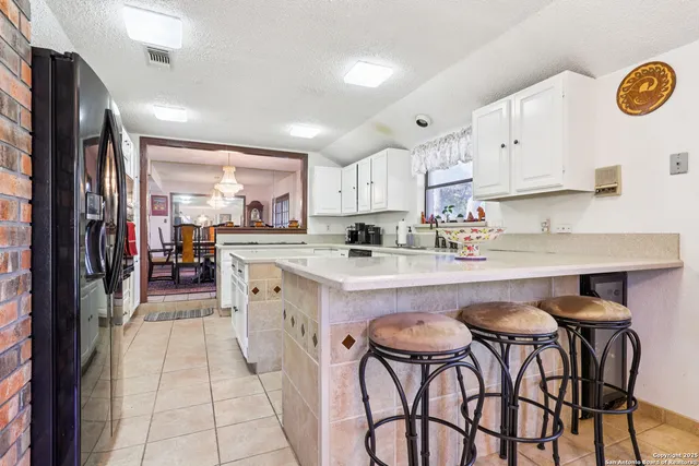 a kitchen with stainless steel appliances granite countertop a table chairs sink refrigerator and cabinets