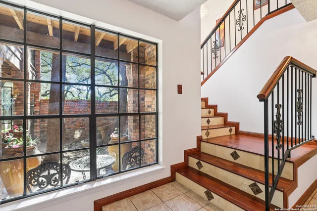 a view of staircase with lots of frames on wall and a window