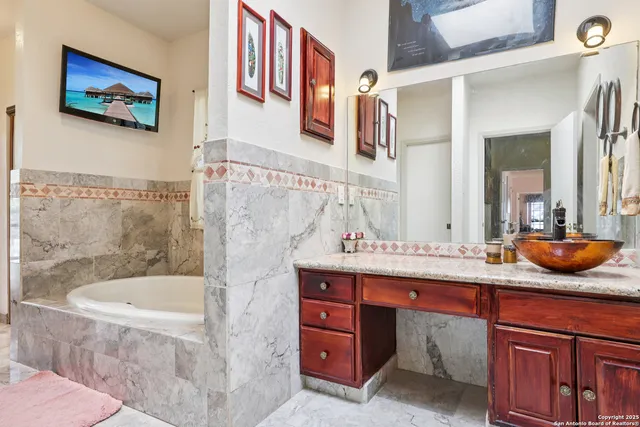 a bathroom with a granite countertop sink a mirror and bathtub