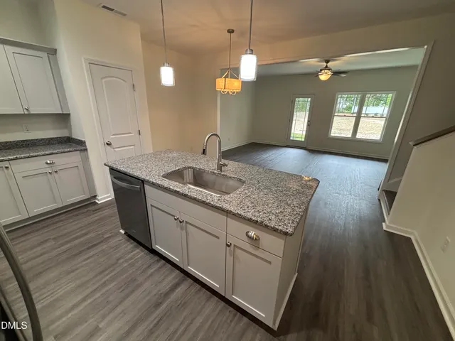 a kitchen with granite countertop a sink cabinets and wooden floor