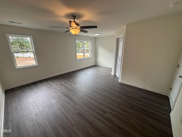 a view of an empty room with a window and wooden floor