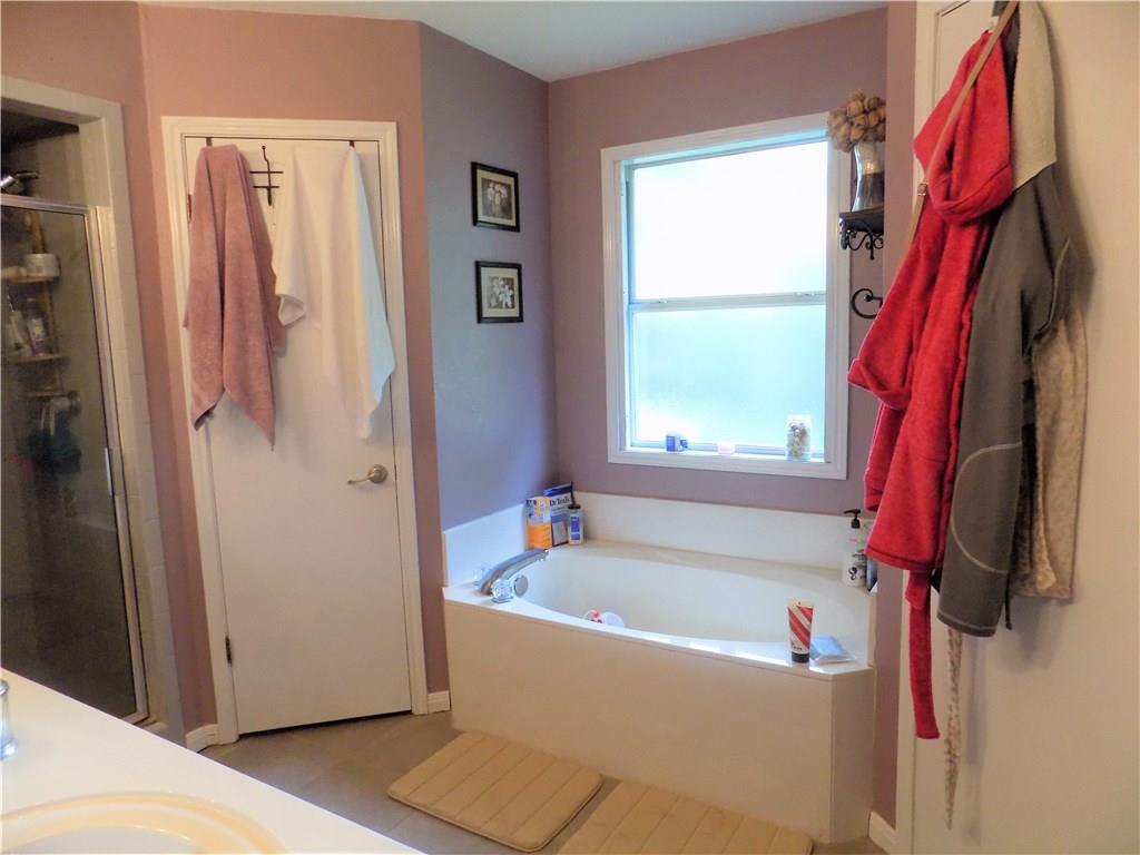 2306 Raintree Path Round Rock, TX 78664 - Photo 12 of 15 Soaking tub with a large privacy window, complemented by a separate glass-enclosed shower