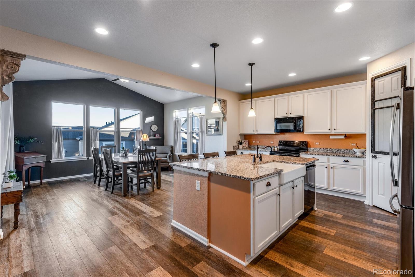 12646 Eagle River Road Firestone, CO 80504 - Photo 15 of 40 a kitchen with stainless steel appliances kitchen island granite countertop a stove top oven a sink a dining table and chairs with wooden floor