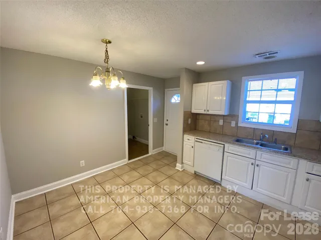 a large kitchen with cabinets and chandelier