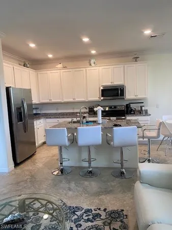a kitchen with stainless steel appliances granite countertop a stove a sink a microwave a refrigerator and cabinets