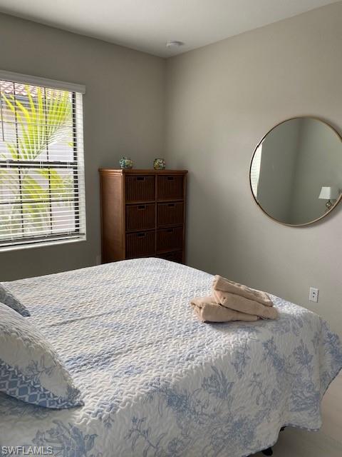 1330 Oceania Drive, Unit 2 Naples, FL 34113 - Photo 22 of 30 a bedroom with a bed and a chandelier