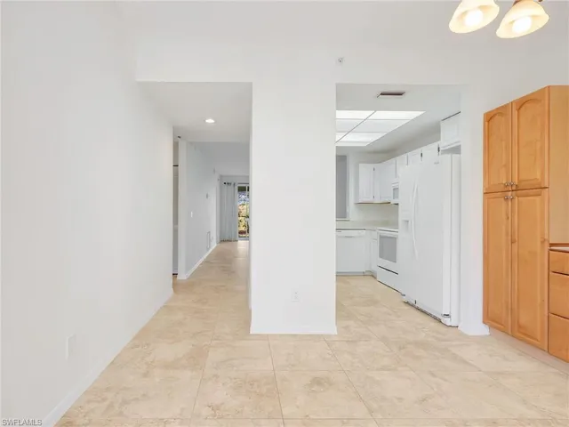 a view of a hallway with wooden floor and a kitchen