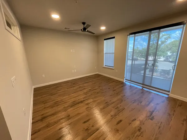 an empty room with wooden floor and windows