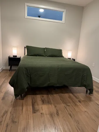 a bedroom with a bed window and wooden floor