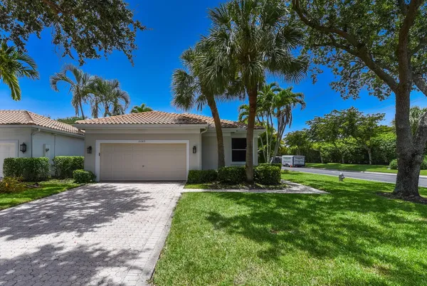 a front view of a house with a yard and palm trees