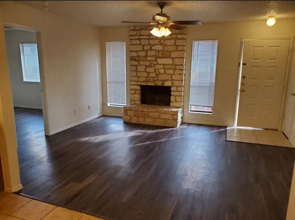 an empty room with wooden floor a fireplace and entryway