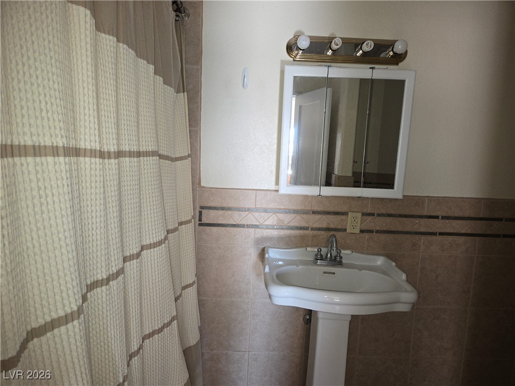 667 C Boulder City, NV 89005 - Photo 5 of 6 Full bath featuring a shower with shower curtain, tile walls, and a wainscoted wall
