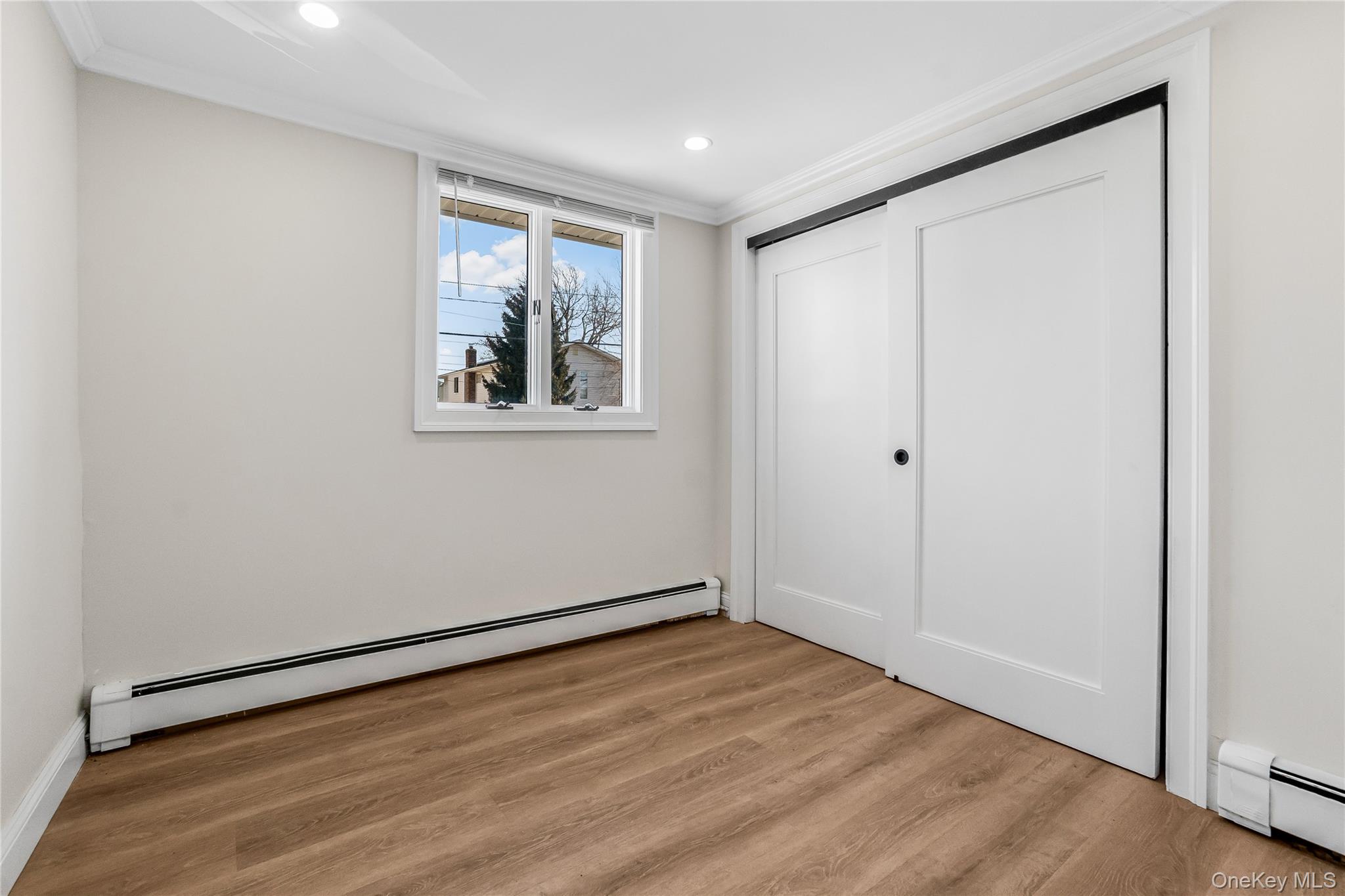 107 Beverly Road Massapequa, NY 11758 - Photo 26 of 30 a view of an empty room with wooden floor and a window