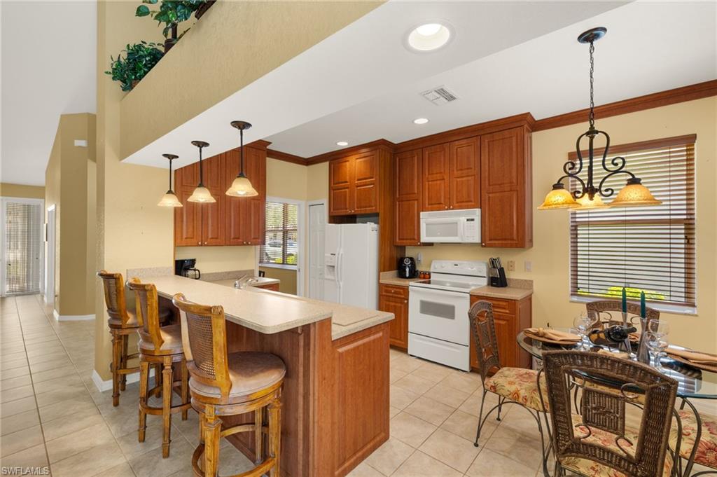 1409 Athol Way, Unit 101 Naples, FL 34104 - Photo 9 of 37 Kitchen featuring visible vents, light tile patterned floors, light countertops, a peninsula, and white appliances