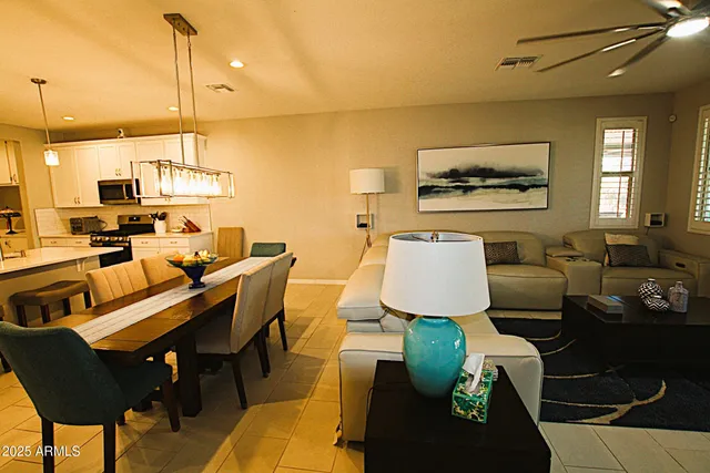 a kitchen with stainless steel appliances kitchen island granite countertop a refrigerator a stove a sink a dining table and chairs with the view of living room