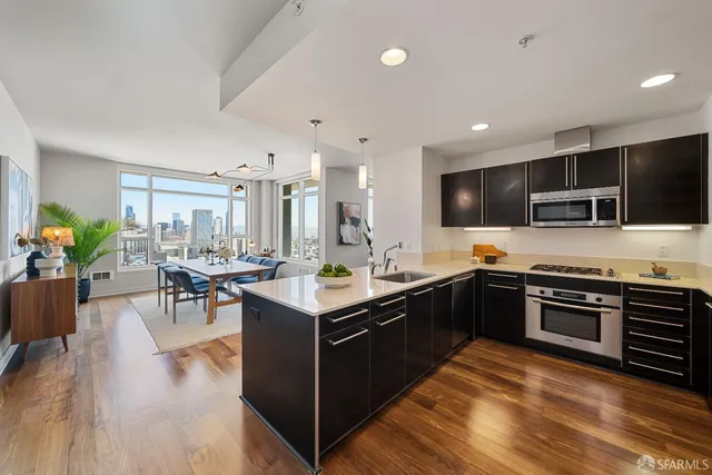 a kitchen with stainless steel appliances granite countertop a stove top oven a sink dishwasher a dining table and chairs with wooden floor