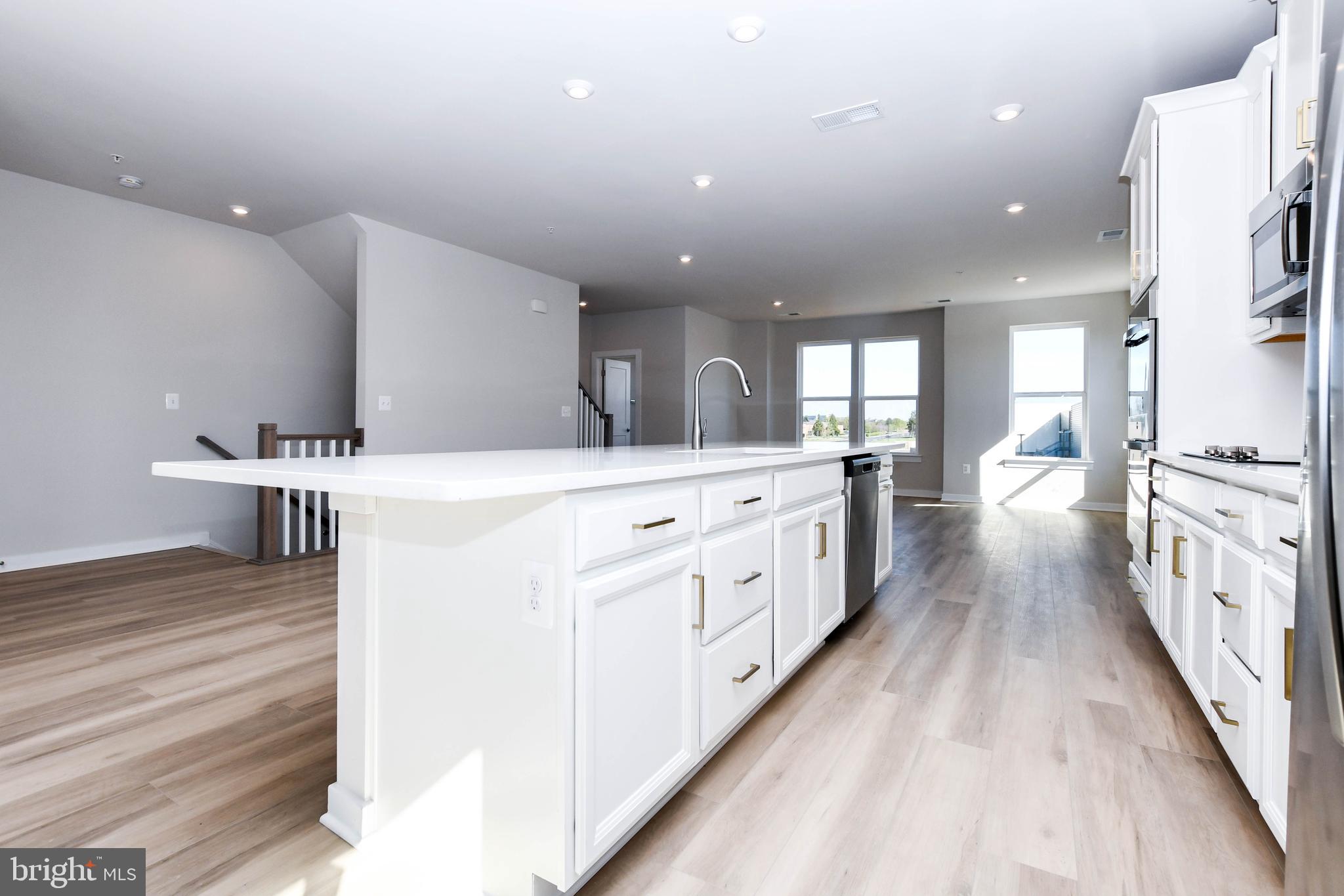 44502 Wolfhound Square Ashburn, VA 20147 - Photo 53 of 100 a large white kitchen with a large counter top a sink a window and stainless steel appliances