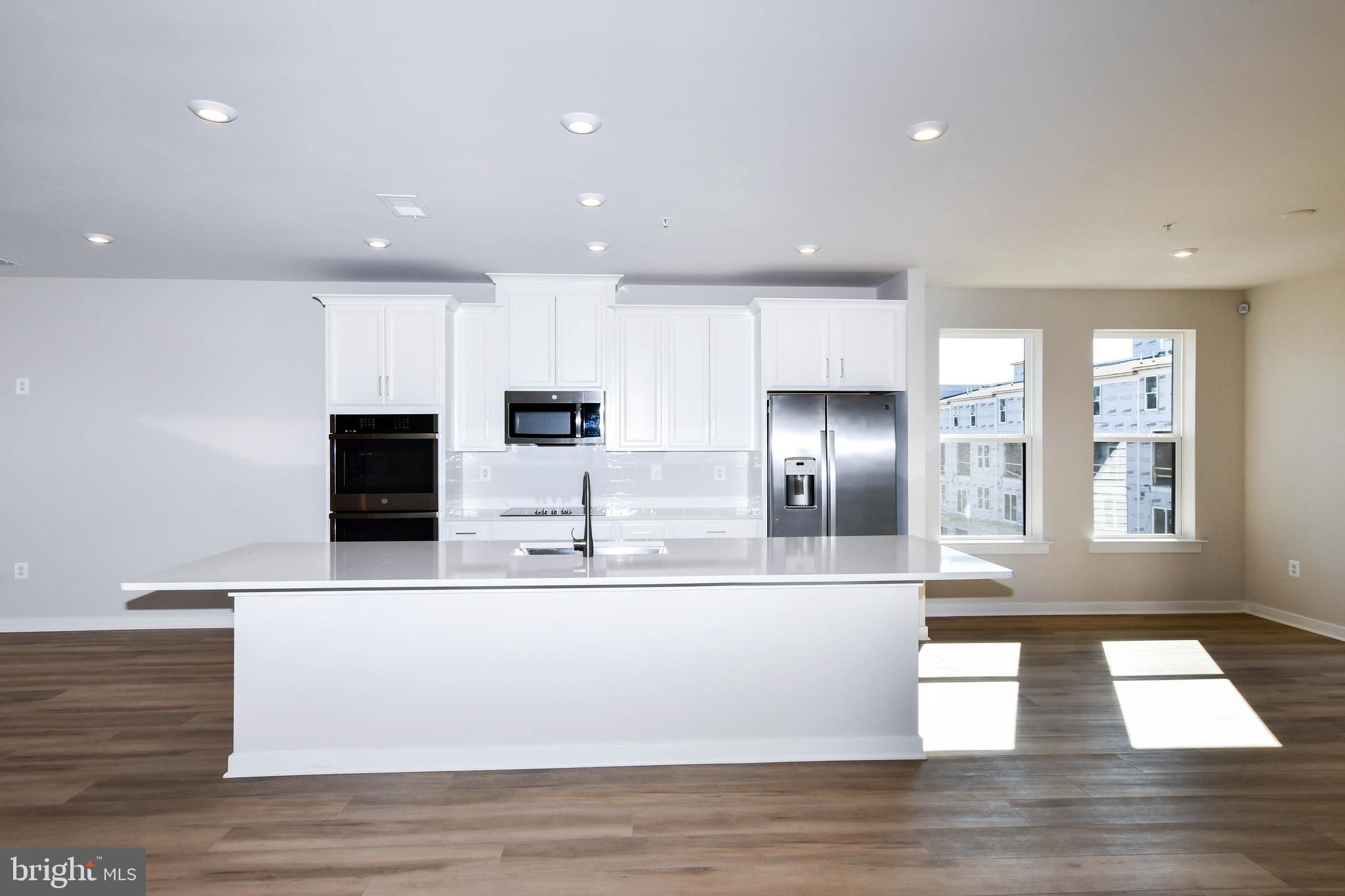 44502 Wolfhound Square Ashburn, VA 20147 - Photo 59 of 100 a large white kitchen with kitchen island a counter top a sink and a stove