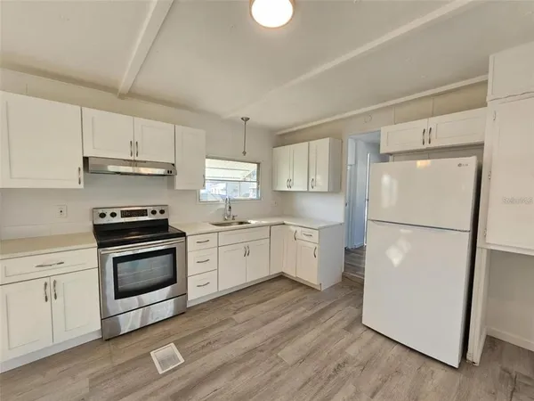 a kitchen with a white cabinets and wooden floor