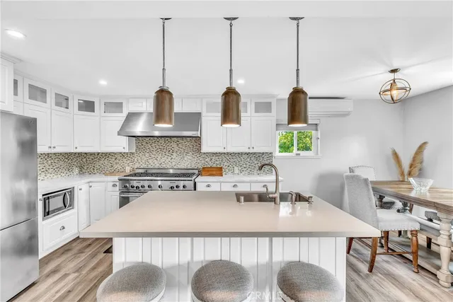 a kitchen with stainless steel appliances granite countertop a sink a stove and a wooden floors