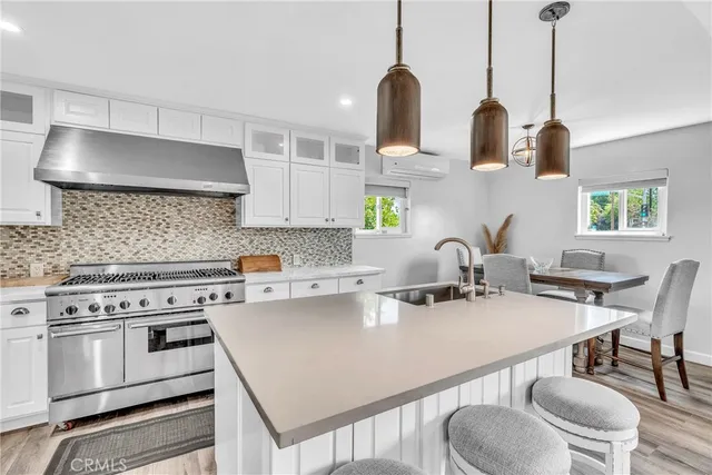 a kitchen with stainless steel appliances a sink a stove a table and chairs