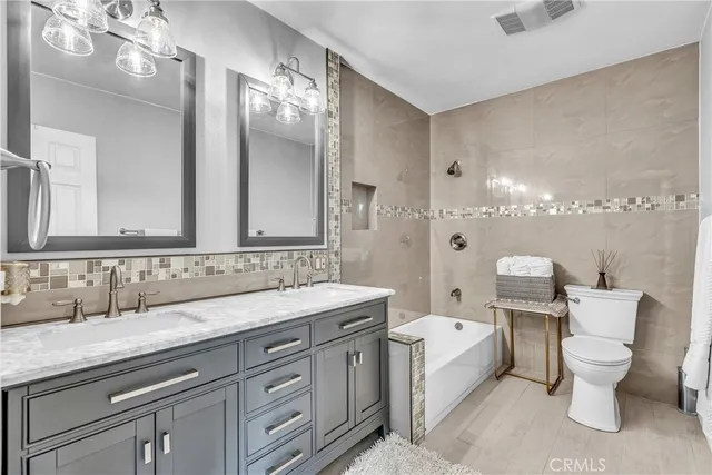 a spacious bathroom with a double vanity sink a toilet and a mirror