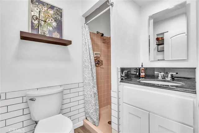 a bathroom with a granite countertop sink toilet and mirror